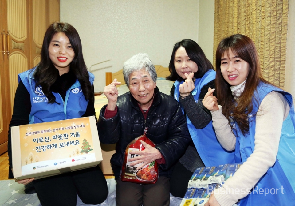 자원봉사자들이 서울 강북구 수유동에 위치한 독거어르신 가정에 방문하여 겨울나기 식료품이 담긴 바구니를 전달하고 기념촬영을 하고 있다.(사진제공=신한생명)