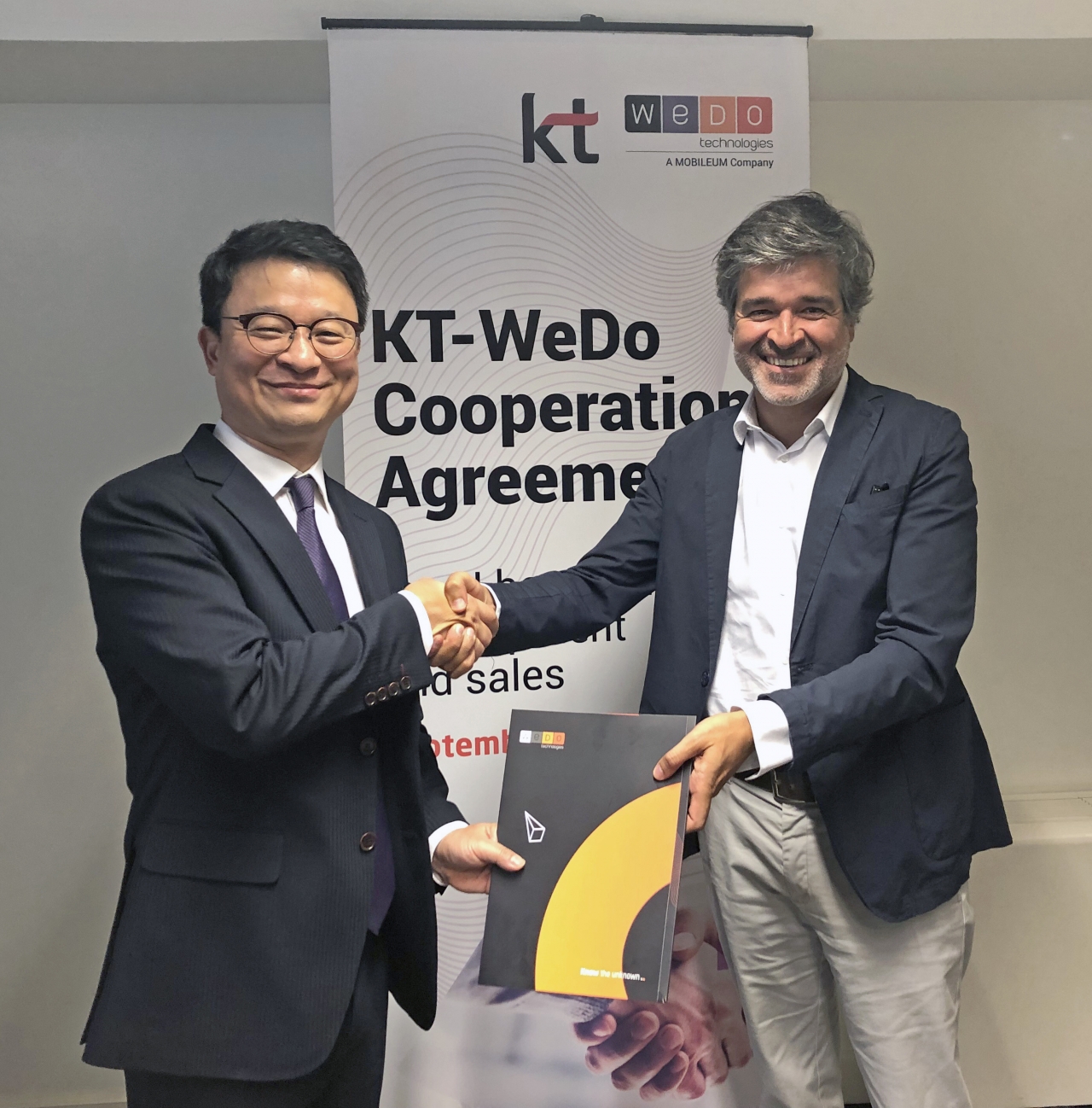 KT 글로벌사업개발본부장 김영우 상무(왼쪽)와 WEDO CEO 루이 패이바(오른쪽)가 계약을 체결하고 악수를 하고 있다.