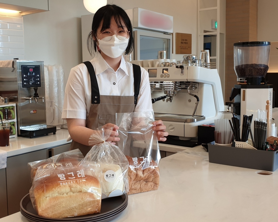 [하이트진로 = 사진] 빵그레 광주점 자활근로 청년 직원이 빵을 포장하고 있다.